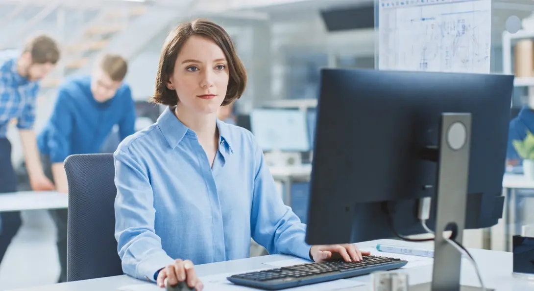 Frau sitzt am PC und nutzt Autodesk Fusion Manage