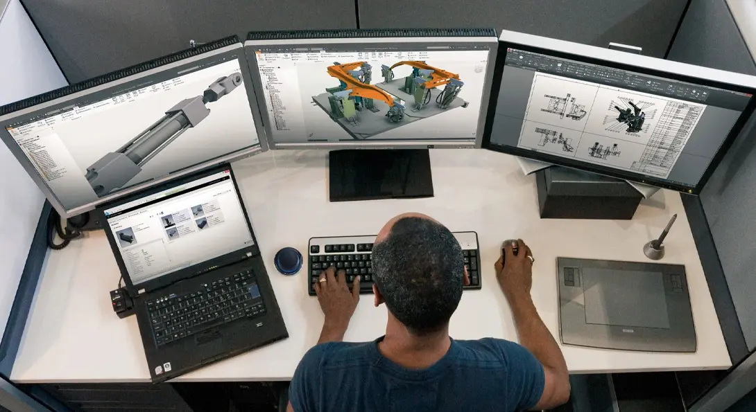 Mann nutzt Autodesk Inventor an drei Bildschirmen im Büro